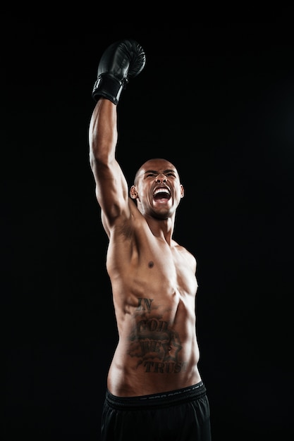 Young afro american boxer celebrating his victory with raised arm in black glove