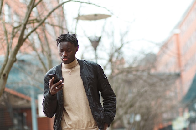 Free photo young afro-american guy using his phone in the streets of lyon in france