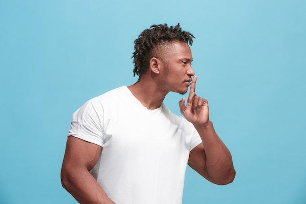 Free photo the young afro-american man whispering a secret behind her hand over blue