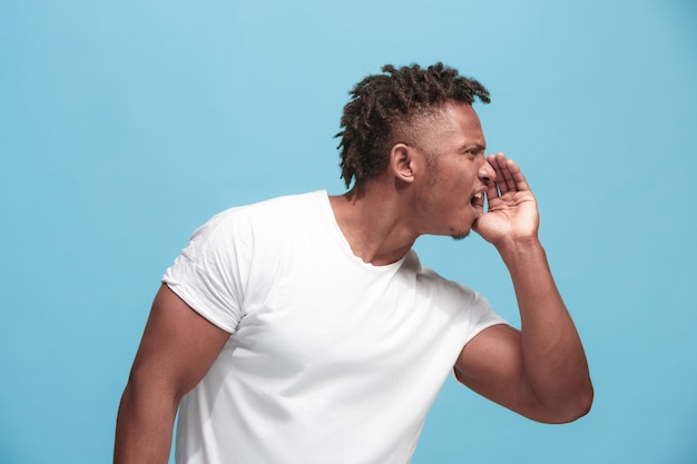 young afro-american man whispering a secret behind her hand over blue