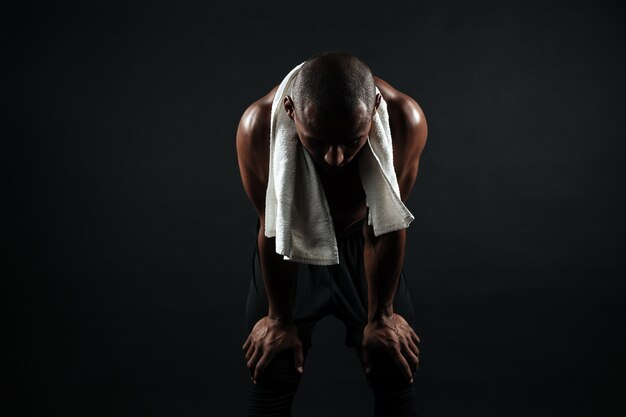 Young afro american sports man standing with white towel, resting after workout