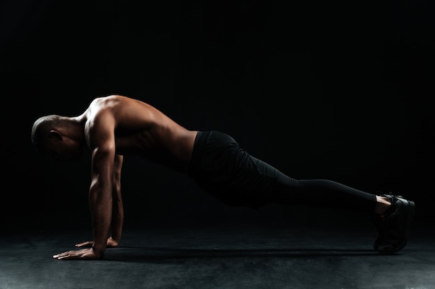 Young afro american sports man with beautiful muscular body doing pushup exercise