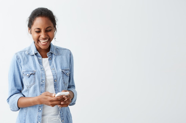 웃 고, 흰 벽을 통해 격리하는 그녀의 친구로부터 메시지를 읽는 동안 행복 식 데 젊은 아프리카 계 미국 흑인 여자. 사람과 기술 개념