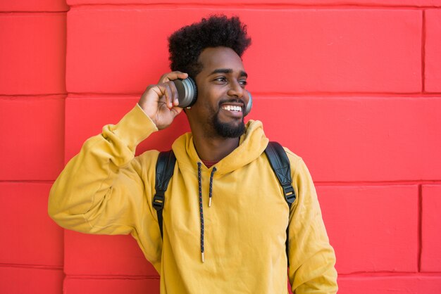 Молодой афро человек слушая музыку с наушниками.