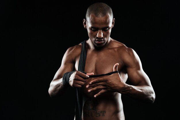 Молодой афроамериканский боксер наматывает боксерские повязки