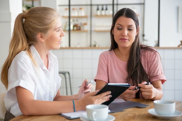 Young agent presenting content on tablet screen to female customer