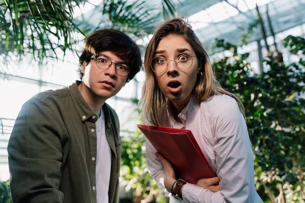 Young agricultural engineers working in big greenhouse