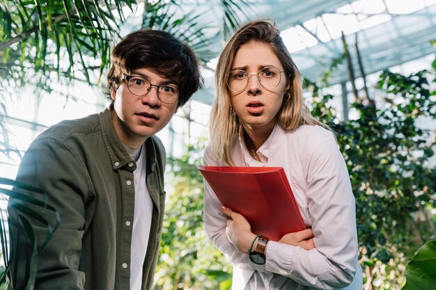 Young agricultural engineers working in big greenhouse