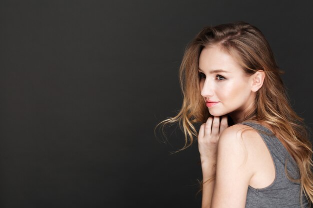 Young amazing woman posing over dark wall