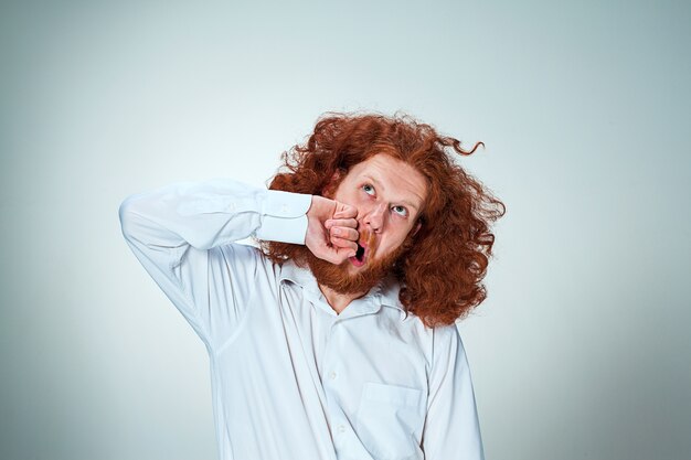 The young angry man with long red hair beating himself