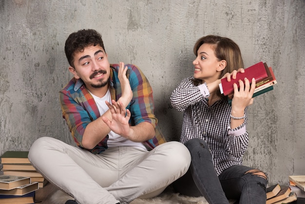 young angry woman hitting to man with books