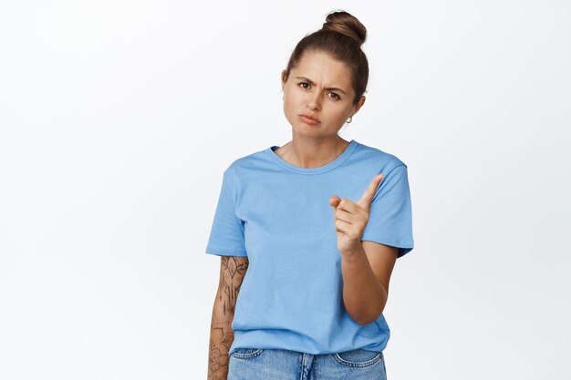 Young angry woman shaking finger, scolding someone bad behaviour, standing disappointed against white background