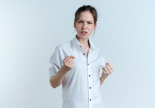 Young annoyed blonde russian girl keeps fists isolated on white space with copy space