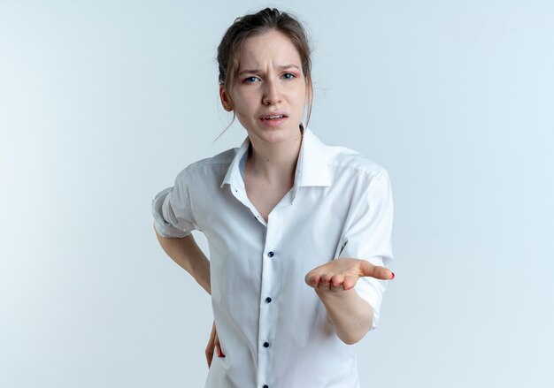 Young annoyed blonde russian girl points at camera with hand isolated on white space with copy space