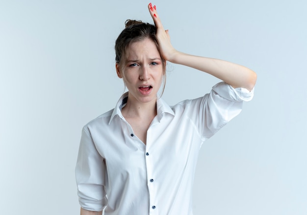 Young annoyed blonde russian girl puts hand on head isolated on white space with copy space