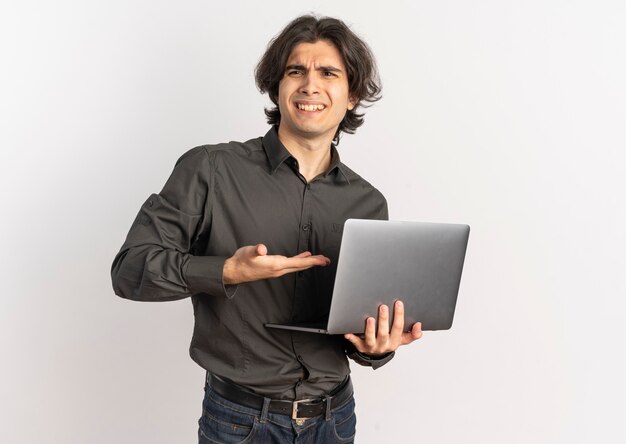 Young annoyed handsome caucasian man holds and points looking at side isolated on white background with copy space