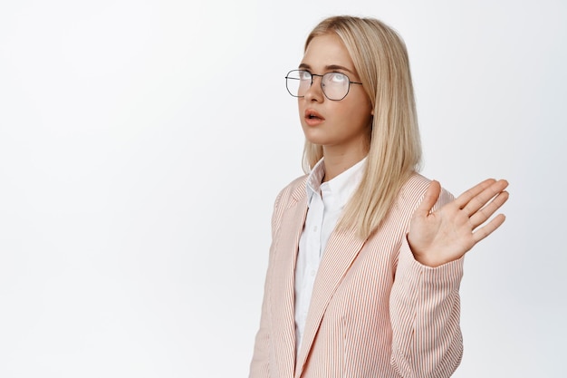 Young annoyed saleswoman wave hand and roll eyes being irritated rejecting offer stop talking sign standing over white background