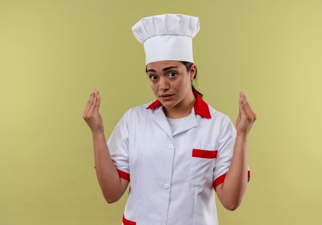 요리사 유니폼에 젊은 불안 백인 요리사 소녀 복사 공간이 녹색 배경에 고립 손을 보유