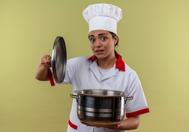 मुफ़्त फोटो young anxious caucasian cook girl in chef uniform holds pot isolated on green background with copy space