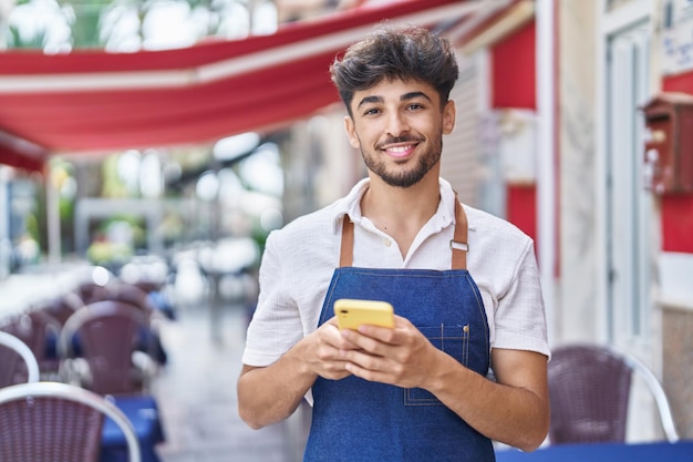 Young arab man waiter using smartphone working at restaurant