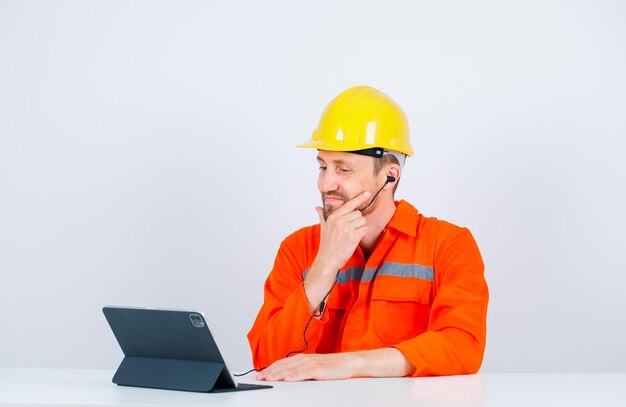 Young architect is looking at tablet by holding hand on chin on white background