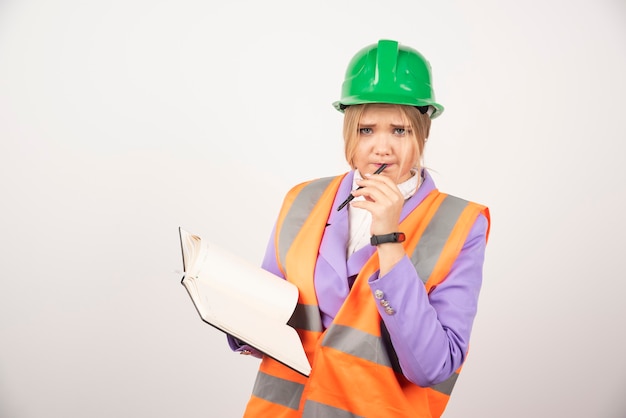 Young architect woman in helmet with tablet on white.