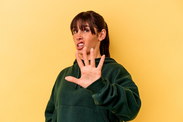 Young argentinian woman isolated on yellow background being shocked due to an imminent danger