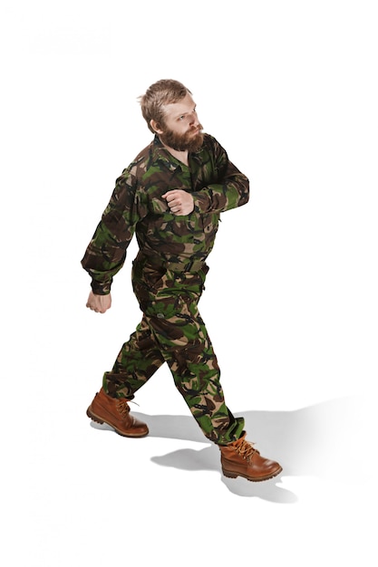 Young army soldier wearing camouflage uniform going isolated on white studio