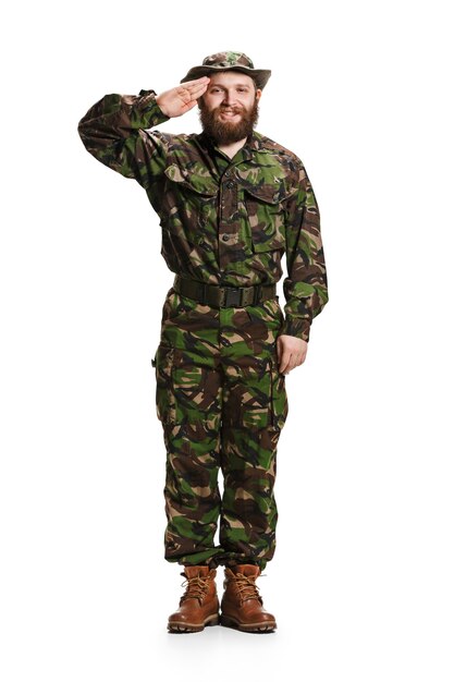 Young army soldier wearing camouflage uniform standing and saluting isolated on white studio background in full-length. Young caucasian model. Military, soldier, army concept. Proffeshional concepts