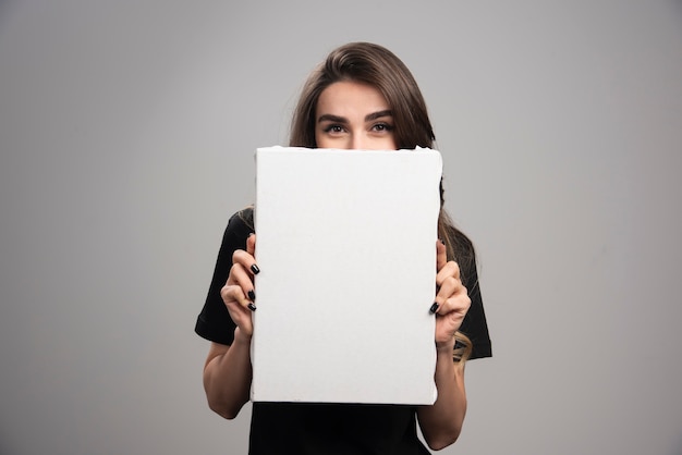 Young artist in black shirt hiding behind canvas. 