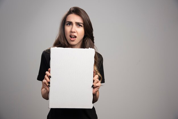 Young artist in black shirt holding empty canvas. 