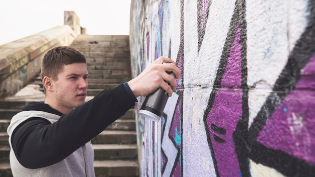 Free photo young artist drawing colorful graffiti on wall