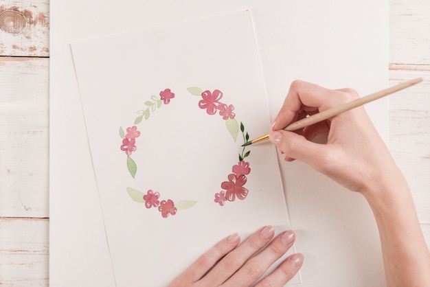 Young artist drawing flowers pattern with watercolor paint and brush at workplace