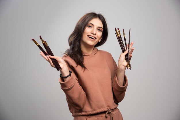 Young artist holding black paint brushes