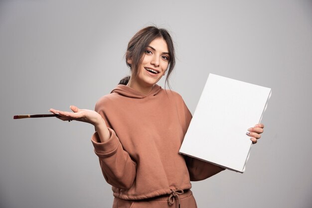 Young artist holding paint brush and canvas