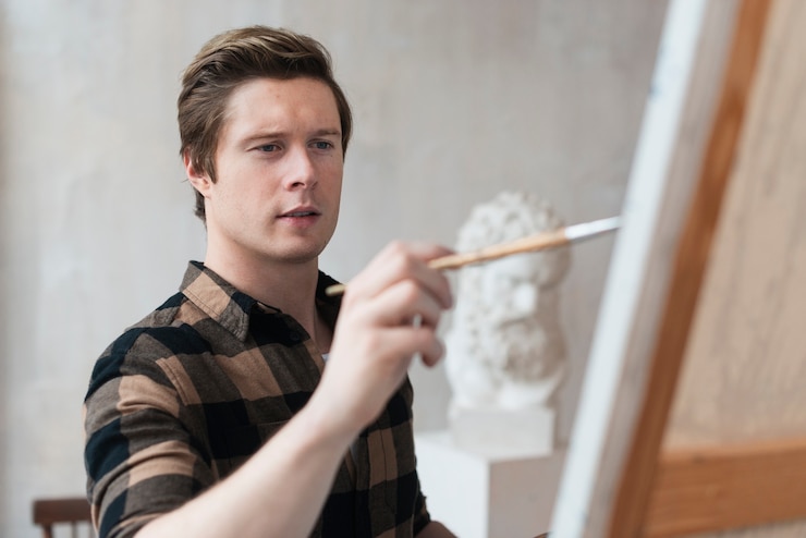 Free Photo young artist painting on canvas