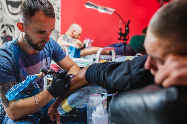 Free photo young artist painting tattoo in studio