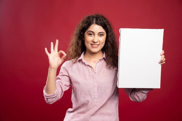 Young artist with empty canvas doing ok sign.