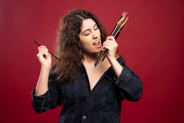 Young artist with paintbrushes standing.