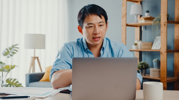 랩톱을 사용하는 젊은 아시아 사업가는 집에서 스마트하게 일하면서 화상 통화 계획에 대해 동료에게 이야기합니다.