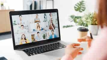 Free photo young asia businesswoman using laptop talk to colleague about plan in video call meeting while work from home at living room.