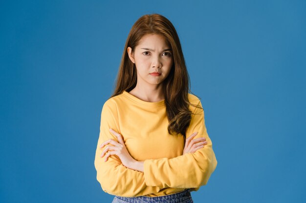 Young Asia lady with negative expression, excited screaming, crying emotional angry in casual clothing and looking at camera isolated on blue background. Happy adorable glad woman rejoices success.