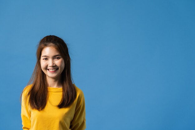 Young Asia lady with positive expression, smile broadly, dressed in casual clothing and looking at camera over blue background. Happy adorable glad woman rejoices success. Facial expression concept.