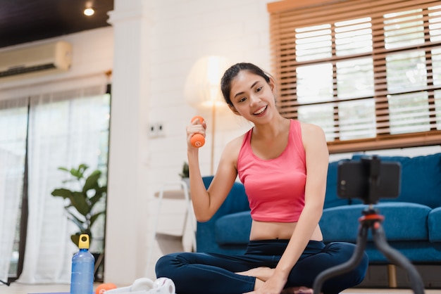 Young Asian blogger woman exercise and looking to camera in living room