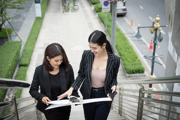 Foto gratuita giovani imprenditrici asiatici con docenti che camminano sulle scale.