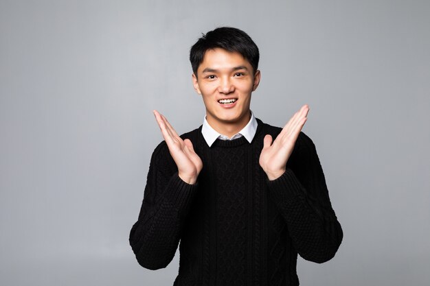 Young asian chinese surprised man standing over isolated white wall