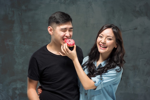 Молодые азиатские пары наслаждаются едой сладкого красочного пончика