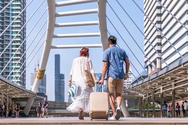 Young asian couple walking with luggage travel summer vacation or honeymoon trip