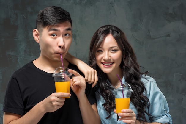 オレンジジュースのグラスを持つ若いアジアカップル