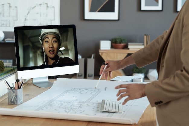 남성 동료와 이야기 하는 컴퓨터 화면에 헬멧에 젊은 아시아 여성 건축업자